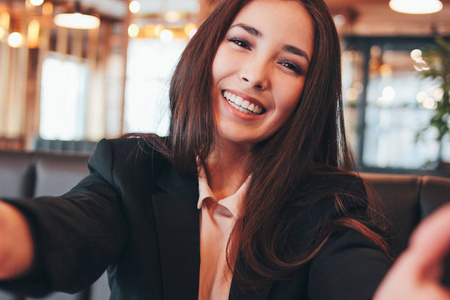 美丽迷人的黑发微笑的亚洲女孩自拍正面相机在咖啡馆。
