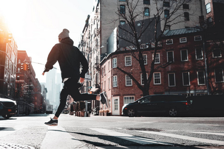 城市男性运动员在沥青上穿过纽约街道。 穿着运动服准备马拉松赛跑的快跑运动员