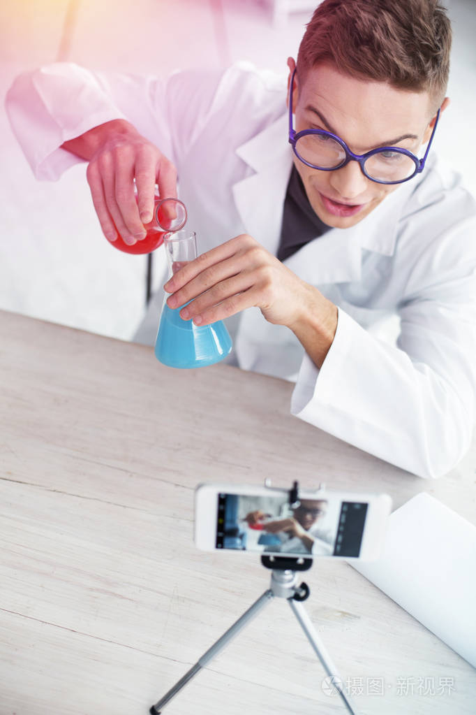 身穿白色实验室外套拍摄化学视频的视频博主