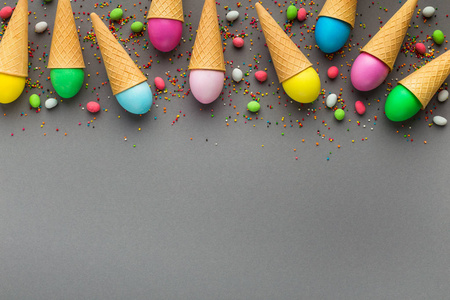 彩色复活节彩蛋在灰色背景的华夫饼锥