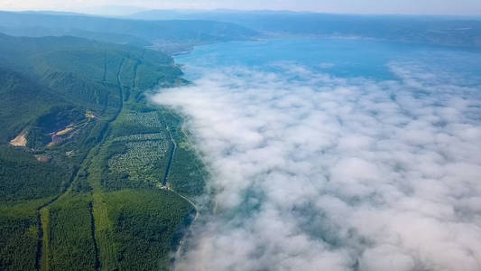 飞在云层之上。 贝加尔湖海岸。 满是森林的山。 俄罗斯从无人机