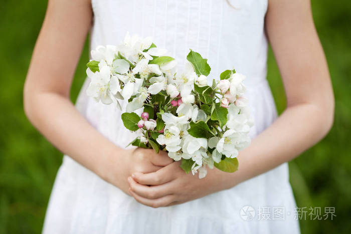 照片 可爱的年轻女孩拿着一束苹果花.