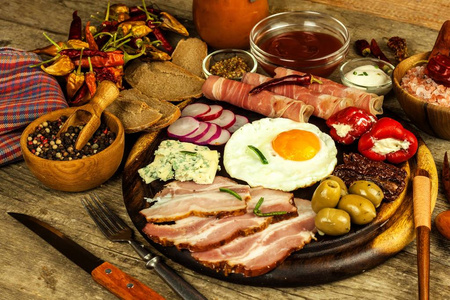 木板上的煎蛋。丰盛的早餐, 包括火腿和蔬菜。鸡蛋和火腿