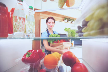 女性站附近打开冰箱充分的健康食品，蔬菜和水果的画像。女性肖像