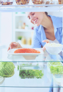 女性站附近打开冰箱充分的健康食品，蔬菜和水果的肖像