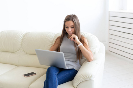 自由职业者和人的概念坐在沙发上和在笔记本电脑上工作的年轻女子