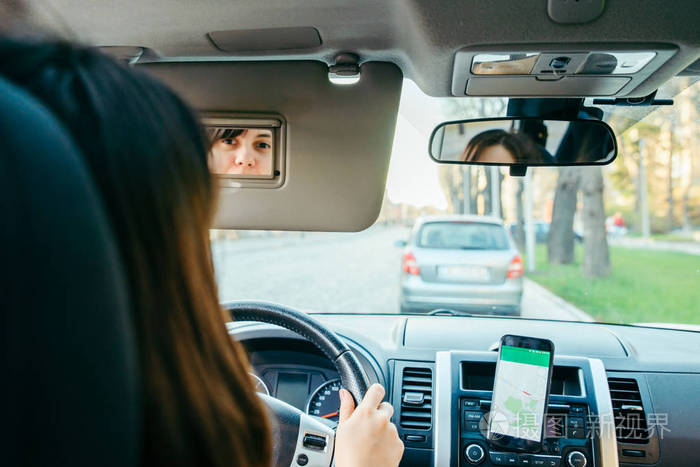 年轻女子驾驶汽车，用手机导航。公路旅行