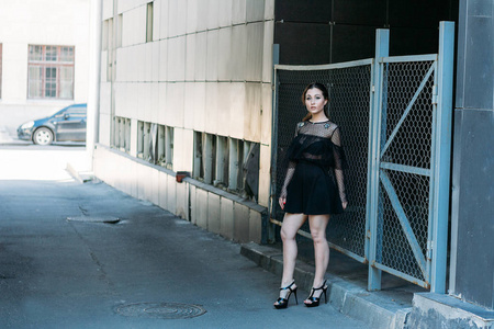 一个女孩的肖像，黑发，穿着黑色的裙子，在拱门里，在城市里。摆姿势，走路。孤独，孤独。