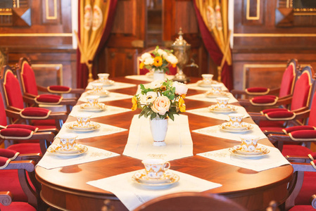 白俄罗斯中世纪城堡餐厅.旧的漂亮的红色椅子和带花的桌子照片