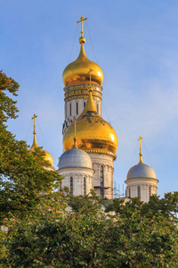 俄罗斯莫斯科2018年9月2日大天使大教堂和伊凡大钟塔在莫斯科克里姆林宫领土上的蓝天和绿树背景在阳光明媚的早晨