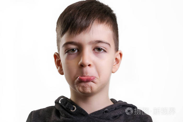 在白色背景下微笑的学龄前男孩的工作室肖像皱眉的面部表情
