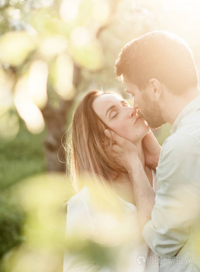 春天的情人在盛开的花园里可爱的春天夫妇亲吻和拥抱