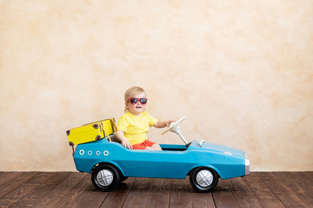 快乐的孩子骑玩具老式汽车。 有趣的孩子在家玩。 暑假及旅游概念