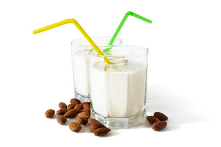 杏仁牛奶在壮观的眼镜与鸡尾酒管和杏仁分离在白色背景