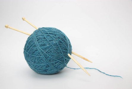 白色背景上的蓝色羊毛和针织针。