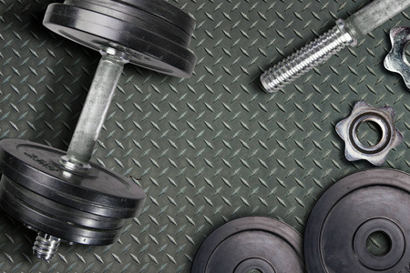 哑铃和重物躺在健身房的地板上。 杠铃装置和健身房设备。 健身俱乐部的金属负荷