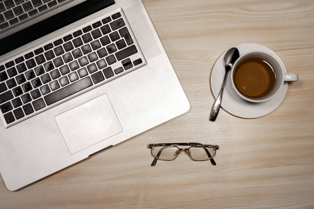 桌子上有笔记本电脑眼镜，木桌上有一杯茶。 顶部视图与复制空间。 平躺图像