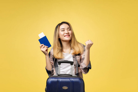 女人旅行。年轻美丽的亚洲女旅客拿着护照, 手提箱和机票站立在黄色