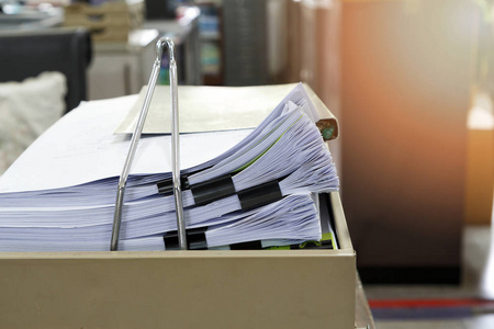将业务文件堆放在办公桌报告文件堆上照片