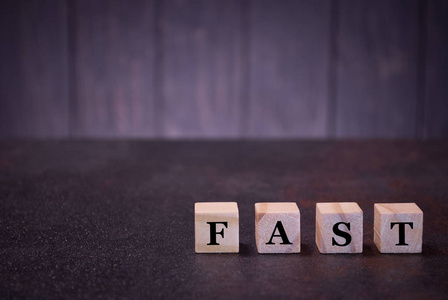 单词fast on wood cubes，on a dark background，light wood cubes signs