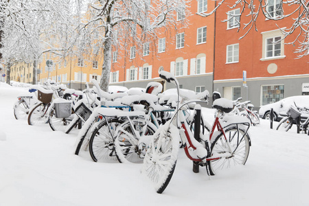 雪的混乱在城市停着自行车覆盖雪树和建筑物的背景。