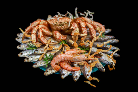 大毛煮蟹坐在一堆咸鱼上，放在一束黑色背景的礼物上，重点放在虾上