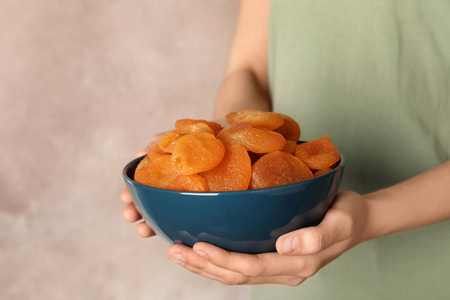 女人拿着碗与干燥杏在颜色背景空间的文本。 健康水果