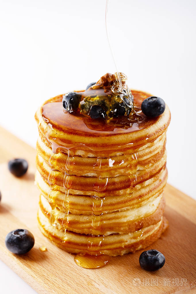 美国甜自制的薄煎饼或煎饼与蓝莓水果坚果和蜂蜜美味的甜点早餐白色