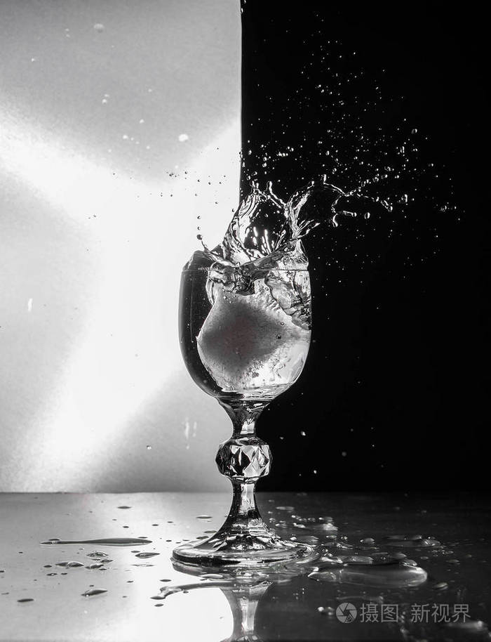 透明玻璃酒杯在腿上,溅在黑白背景上