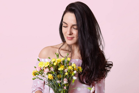 高兴,高兴,深色头发,年轻的女人闻起来愉快的气味,从花,穿着时尚的