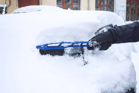 在降雪期间，人们用刷子和刮刀工具从雪和冰中清洗汽车。 冬季紧急情况。 天气相关的车辆紧急情况。 覆盖着雪的汽车