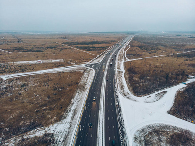 从无人机到冬季沥青公路或农村高速公路的空中或顶部景观, 有汽车和货运物流卡车交通