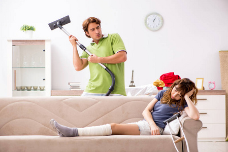 丈夫帮助腿受伤的妻子在家务图片