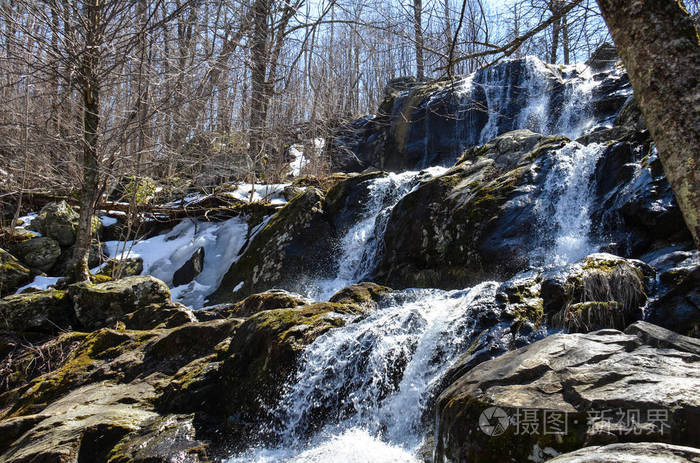在深空瀑布的春天，一个瀑布位于弗吉尼亚的神南多阿国家公园内，沿着天际线行驶在蓝色的山脊山脉中