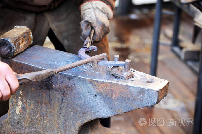 铁匠在锻铁砧上用锤子加工金属