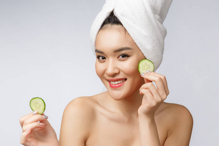 美丽的年轻亚洲妇女皮肤护理图像与黄瓜在白色背景工作室