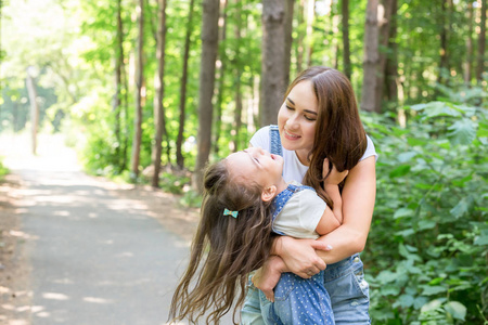 家庭和自然概念母亲和孩子在绿色公园玩耍的肖像