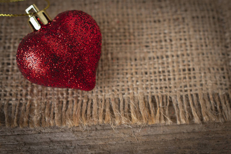 红色塑料心脏放在麻袋和木桌上。