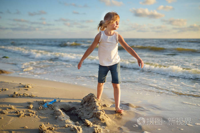 可爱的小女孩在沙滩上玩在温暖和阳光明媚的夏日海边玩