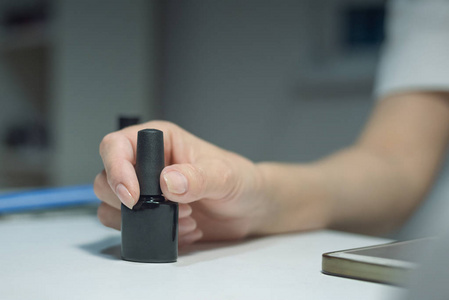 美甲师大师手中的黑色指甲油瓶。 指甲护理概念。