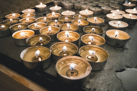 在黑暗的背景上燃烧纪念蜡烛。烛台上有许多圆形的纪念蜡烛。在桌子上的蜡烛上燃烧着火。