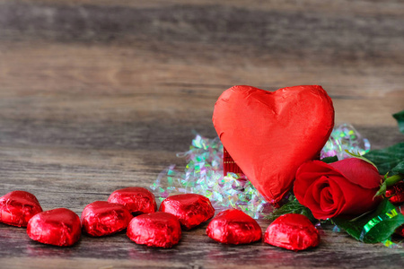 放在木地板上的红色心形巧克力和玫瑰，留出写信的空间
