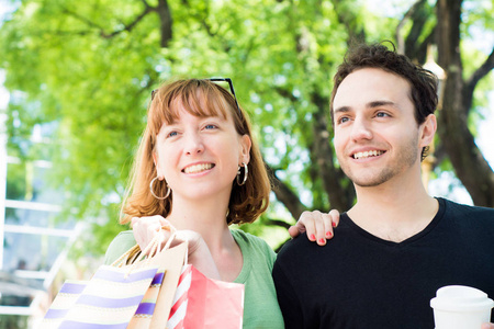 幸福的年轻夫妇带着购物袋在街上散步。 消费主义概念。