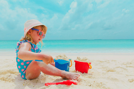 可爱的小女孩在沙滩上玩沙子和玩具