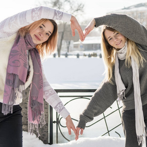 冬天，两个女人在雪城的背景上做了一个心形图案