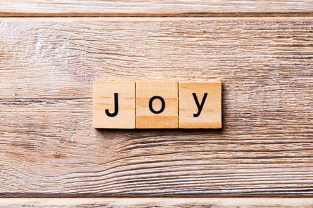 写在木块上的快乐词。 欢乐文字在木桌上为您的设计概念。