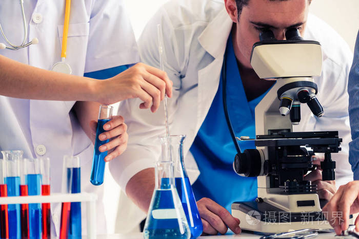 着实验室外套在实验室工作,同时检查试管和科学仪器中的生物化学样品