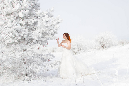 新娘站在一棵覆盖着霜冻的圣诞树附近。 冬季肖像画