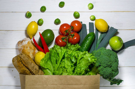 白色木质背景的不同健康食品纸袋。俯视图