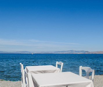 白色餐厅桌子在海滩上的暑假和夏季概念。 提供海景的完美午餐